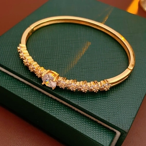 Close-up of gold plated flower bracelet with cubic zirconia on a dark green jewelry box