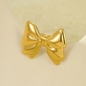 Macro shot of elegant golden bow metal ring with mirror finish on minimalist background