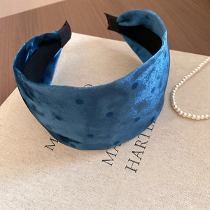Detail of blue velvet polka dot headband on a vintage book with pearl necklace