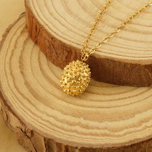 18k gold plated stainless steel durian pendant necklace displayed on natural wood slabs