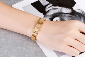 Macro dettaglio del bracciale a maglia dorata con ciondoli a luna e fiocco di neve e zirconi