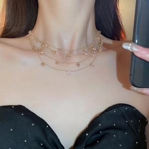 Detail einer mehrlagigen Goldkette mit rosa Zirkonia-Anhängern am Hals des Models