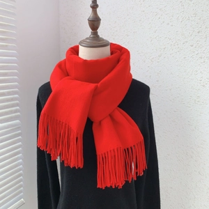 Detail of red faux cashmere scarf with elegant tassels styled on a black coat