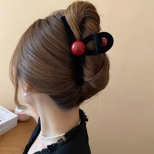 Detail of red bead accents on black velvet hair claw clip worn in a bun hairstyle