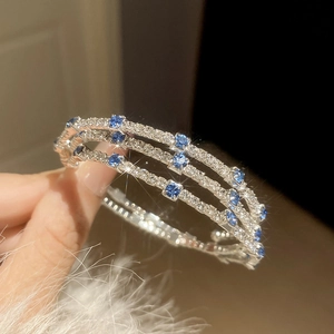 Macro shot of silver three-layer cuff bracelet with blue square zircons and white crystals