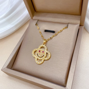 Gold-plated flower smiley necklace with red and clear crystals in a jewelry box