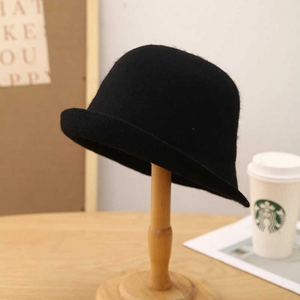 Elegante cappello cloche in lana nera da donna con tesa arrotolata su supporto in legno