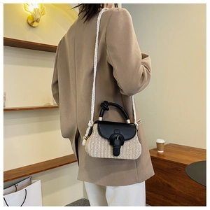 Detail of hand-woven straw crossbody bag with black leather accents and rope strap