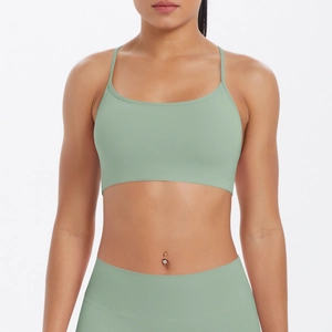 Gros plan d'une brassière de yoga vert sauge avec bretelles fines et bande de soutien