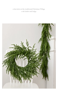 Detail of realistic green Norfolk pine wreath and garland set on a white wooden chair