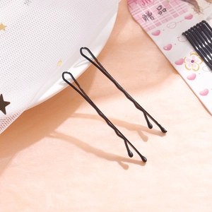Detail view of wavy black metal bobby pins with rounded tips on a decorative display