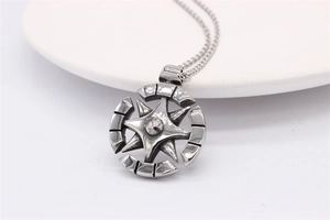 Détail d'un pendentif boussole argenté vintage avec étoile sur socle en céramique