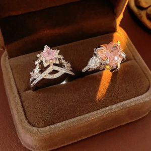 Close-up of silver rings with pink star and heart zircons in a brown velvet box