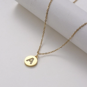 Macro detail of gold round pendant with micro-pave zircon letter A on stainless steel chain