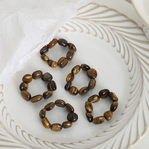 Tiger eye beaded elastic rings set on decorative white plate with soft gauze background