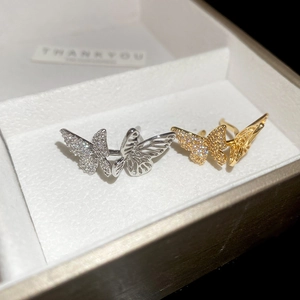 Macro shot of gold and silver hollow butterfly ear cuffs with sparkling zircons