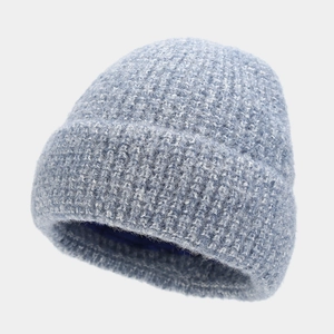 Detail of light blue chunky knit beanie with cuffed design and warm dark blue lining