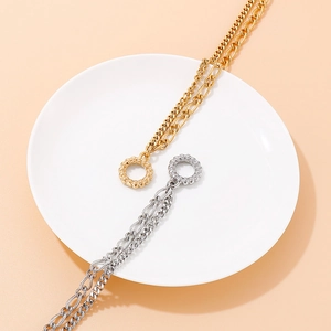 Detailed view of gold and silver chunky chain necklaces with OT toggle clasps on a ceramic plate