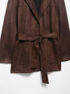 Détail de la veste en similicuir marron avec ceinture à la taille et boutons vintage
