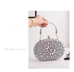 Macro shot of silver evening clutch bag featuring full rhinestones and a gold metal handle