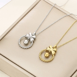 Détail de colliers avec pendentif nœud et cloche en argent et or sur fond beige
