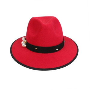 Detail of red fedora hat featuring black ribbon band with pearl and gold metal accents