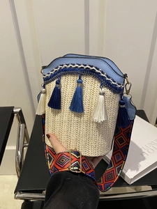 Detail of woven straw bucket bag with blue leather trim and colorful geometric strap