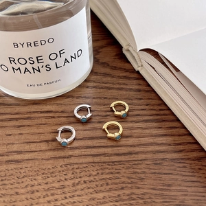 Close-up of gold and silver turquoise hoop earrings on a dark wooden surface