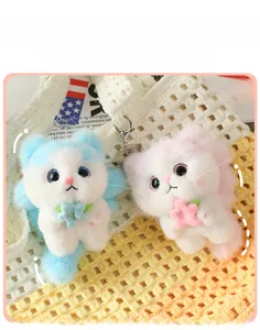 Close-up of plush cat keychains in blue and pink with fluffy texture and floral charms