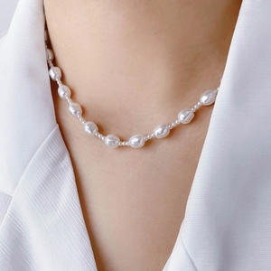 Elegant baroque pearl necklace worn by a model in a minimalist white collared shirt
