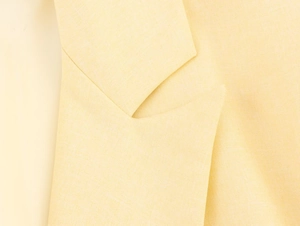 Detail of light yellow blazer lapel showing fine woven texture and premium stitching