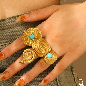 Detail of bohemian gold rings with turquoise and shell on denim fabric background