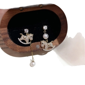 Elegant gold plated rocking horse earrings with pearls and crystals on velvet