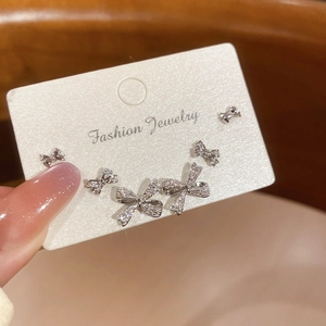 Detail view of silver bow earrings set with sparkling zircons held on a display card