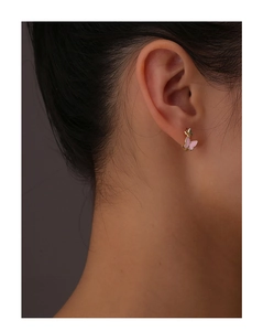 Detail shot of a model wearing elegant pink butterfly earrings with gold metallic edges