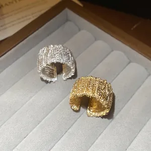 Textured wide open ring set in gold and silver finish with detailed woven metal patterns