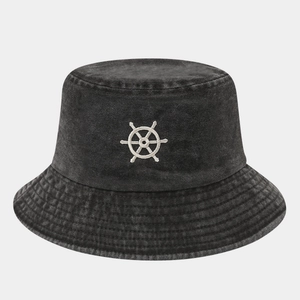 Detailed close-up of white helm embroidery on a charcoal grey washed denim bucket hat