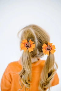 Detail of Halloween pumpkin hair clips on a girl's twin ponytails in orange ribbon