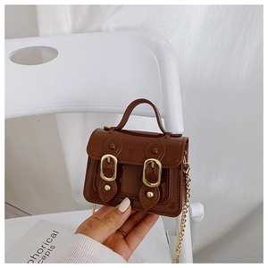 Detail of a brown glossy mini jelly crossbody bag with double magnetic gold buckles