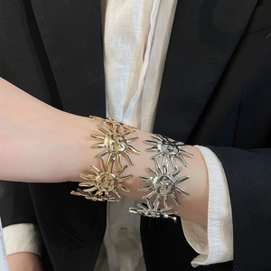Nahaufnahme von modischen, sonnenförmigen Armreifen in Gold und Silber für Damen.