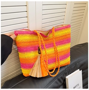 Detail of colorful rainbow straw tote bag with a large tassel charm on a leather sofa