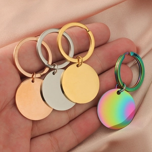 Hand holding four round stainless steel keychains in gold, silver, rose gold and rainbow