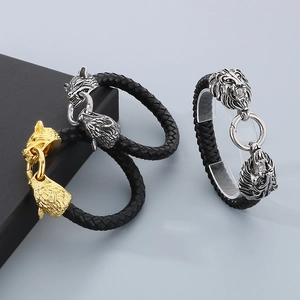 Close-up of woven leather bracelets with silver and gold lion and wolf head metal clasps