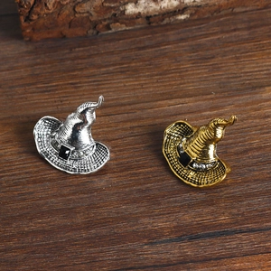 Retro witch hat brooches in gold and silver metal finishes on a dark wood background