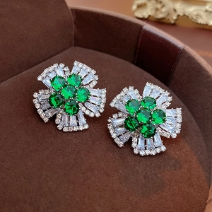 Macro shot of flower earrings with emerald green center and white zircon petals in box