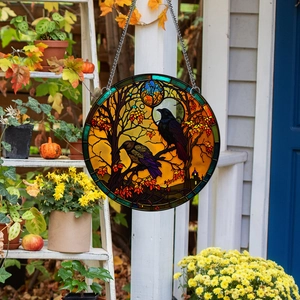 Detail of round acrylic Halloween ornament with crows on a porch with pumpkins