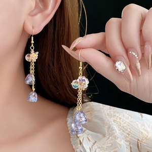 Detailed close-up of golden flower earrings with faceted purple crystal pendants
