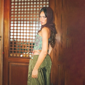 Detail of green camo corset top paired with olive cargo pants against a vintage wood door