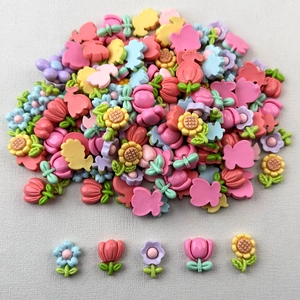 Detailed view of colorful resin tulip and sunflower charms for DIY crafts and hair clips