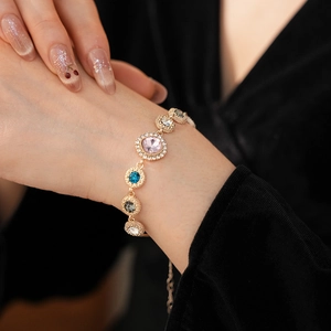 Detailed close-up of a gold-plated bracelet with vibrant colorful diamond inlays on a wrist